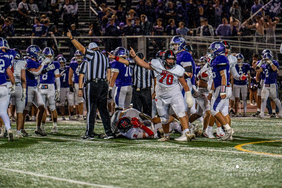 Manalapan's number 70 points to the sky as the referee signals the end of the play.